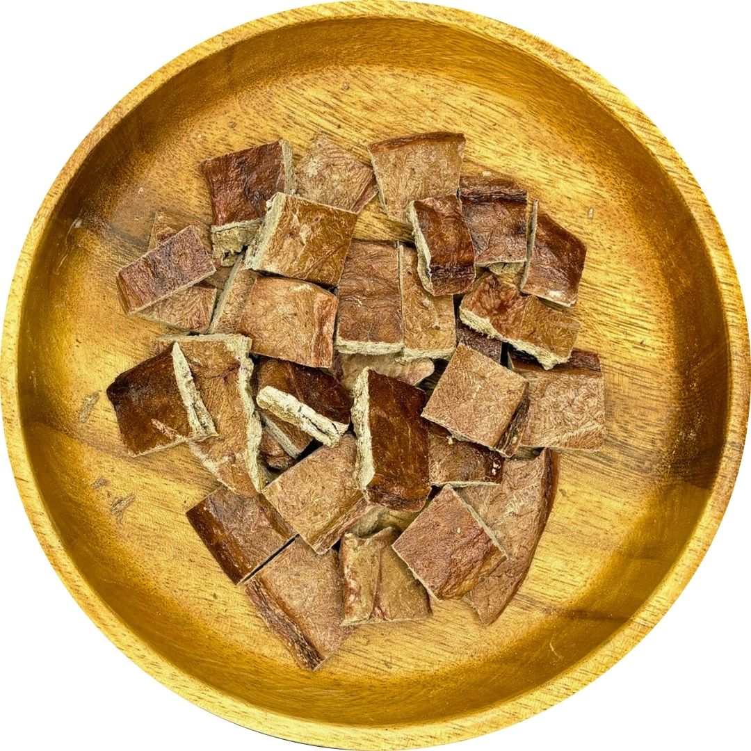 Beef lung dog treats displayed in a wooden bowl, freeze-dried and cut into small squares for easy snacking.