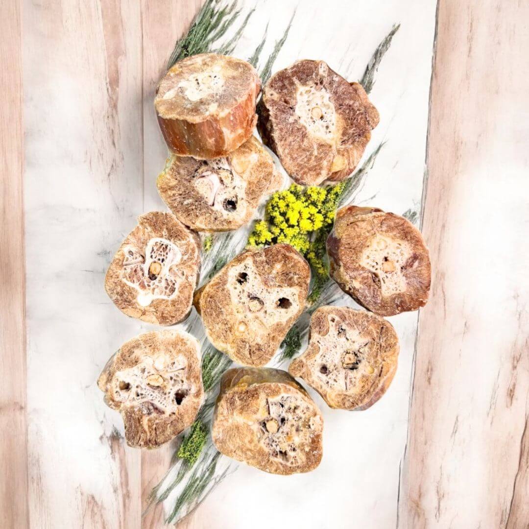 Turkey Neck Dog Treats – Freeze-Dried Medallions arranged on a wooden surface with greenery.