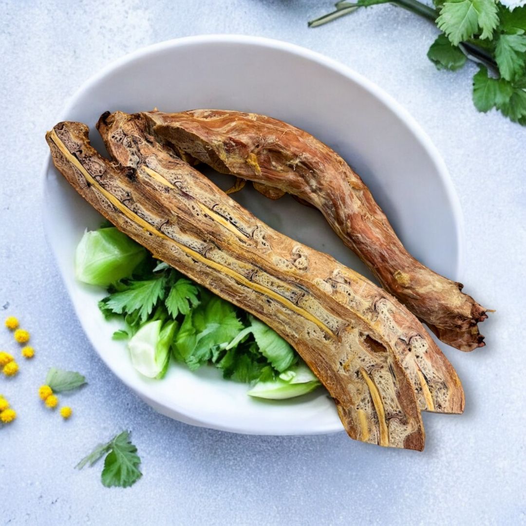 Picture of turkey necks which have been cut in half and then freeze dried. They are placed in a white bowl with parsley. The background is textured and has yellow flowers.