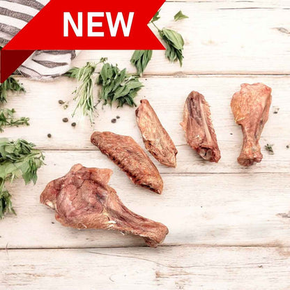 Freeze dried duck wings dog treats arranged on a wooden surface, garnished with herbs and labeled as new.