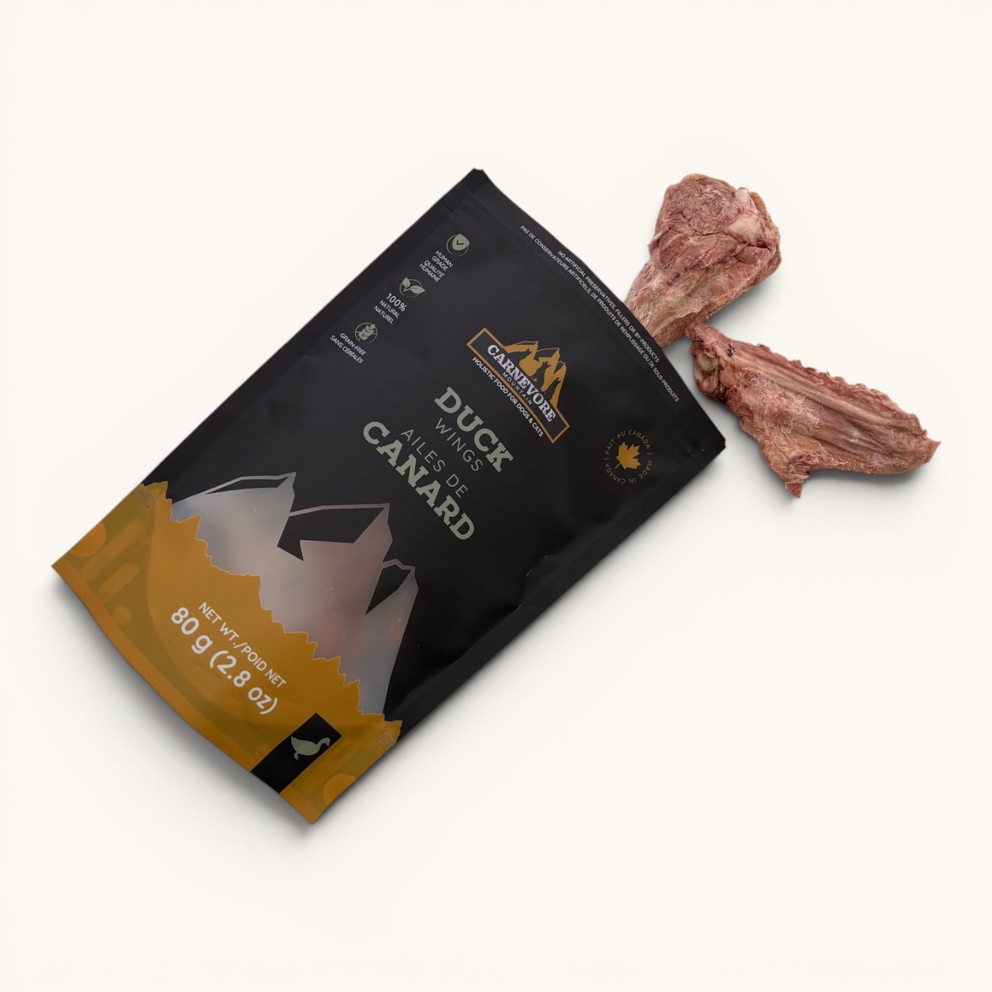 Freeze dried duck wings dog treats falling out of  a resealable bag, featuring a mountain design and nutritional information.